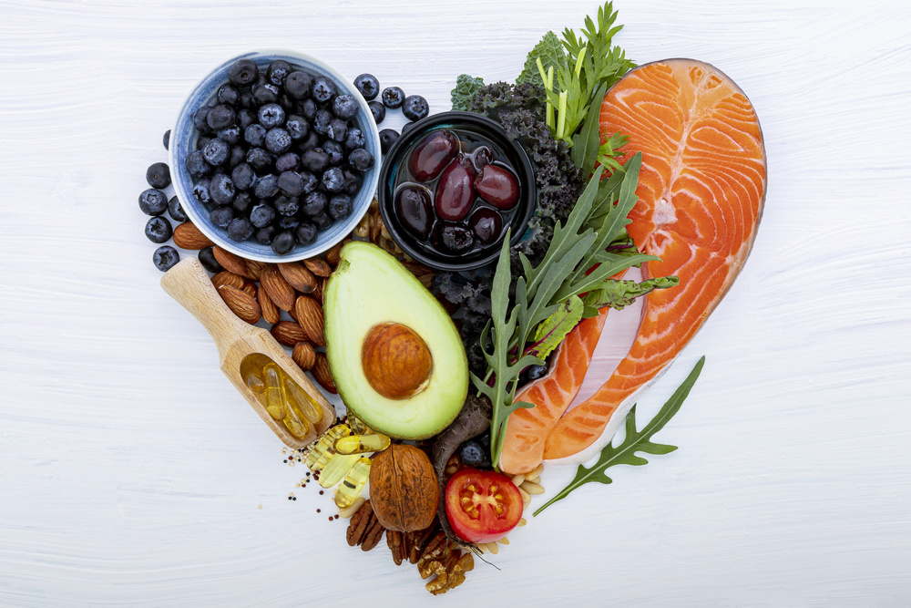 Heart shape of ketogenic low carbs diet concept. Ingredients for healthy foods selection on white wooden background. Balanced healthy ingredients of unsaturated fats for the heart and blood vessels