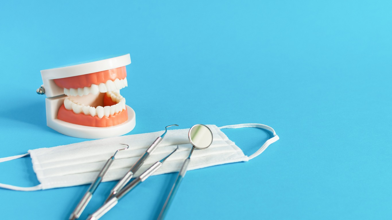 Dental tooth model with dentistry tools for teeth dental care and treatment on blue background.