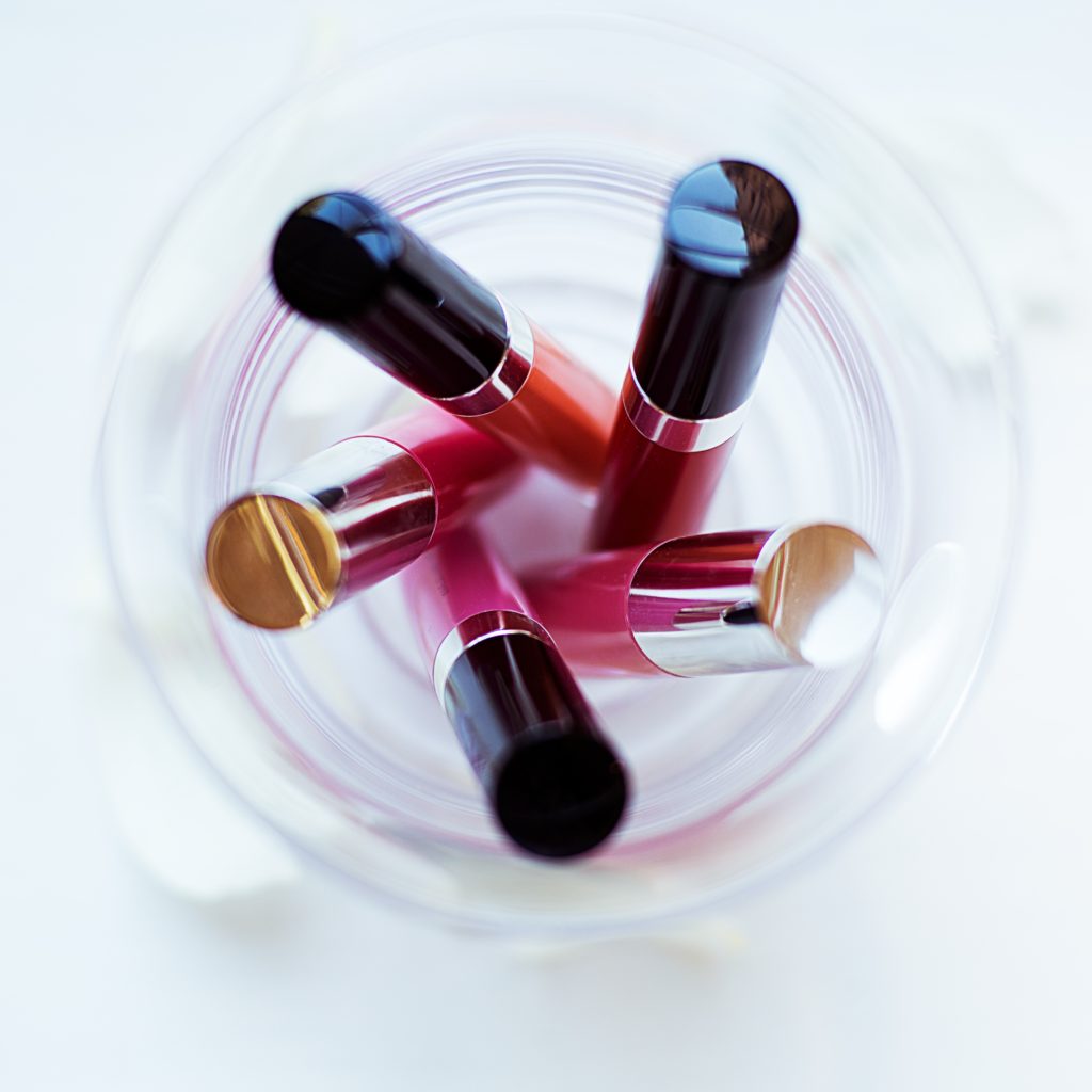 Five Assorted-color Liquid Lipsticks Placed on Glass