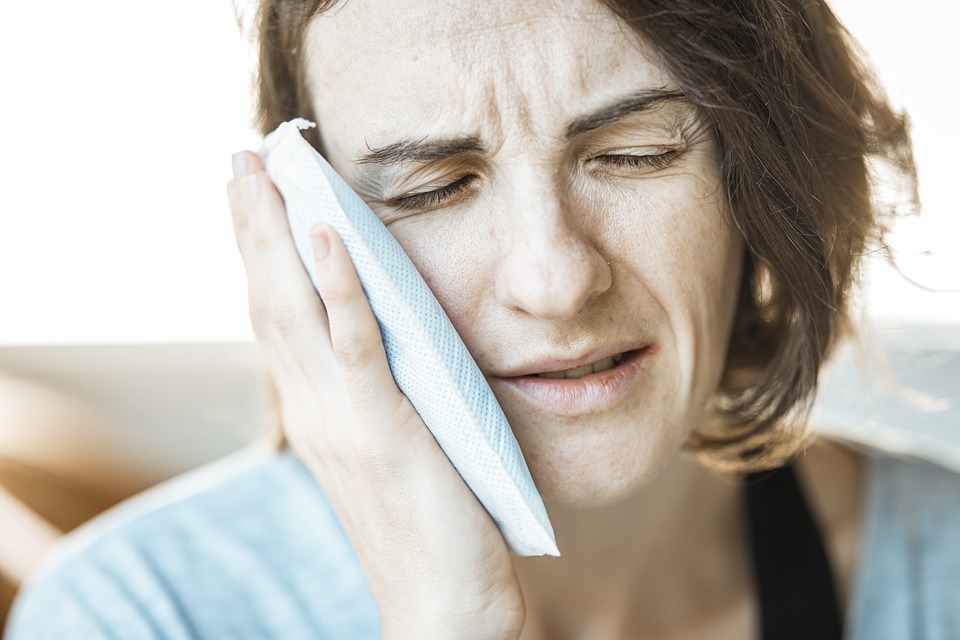 lady applying a cold compress to relieve sharp pain toothache 