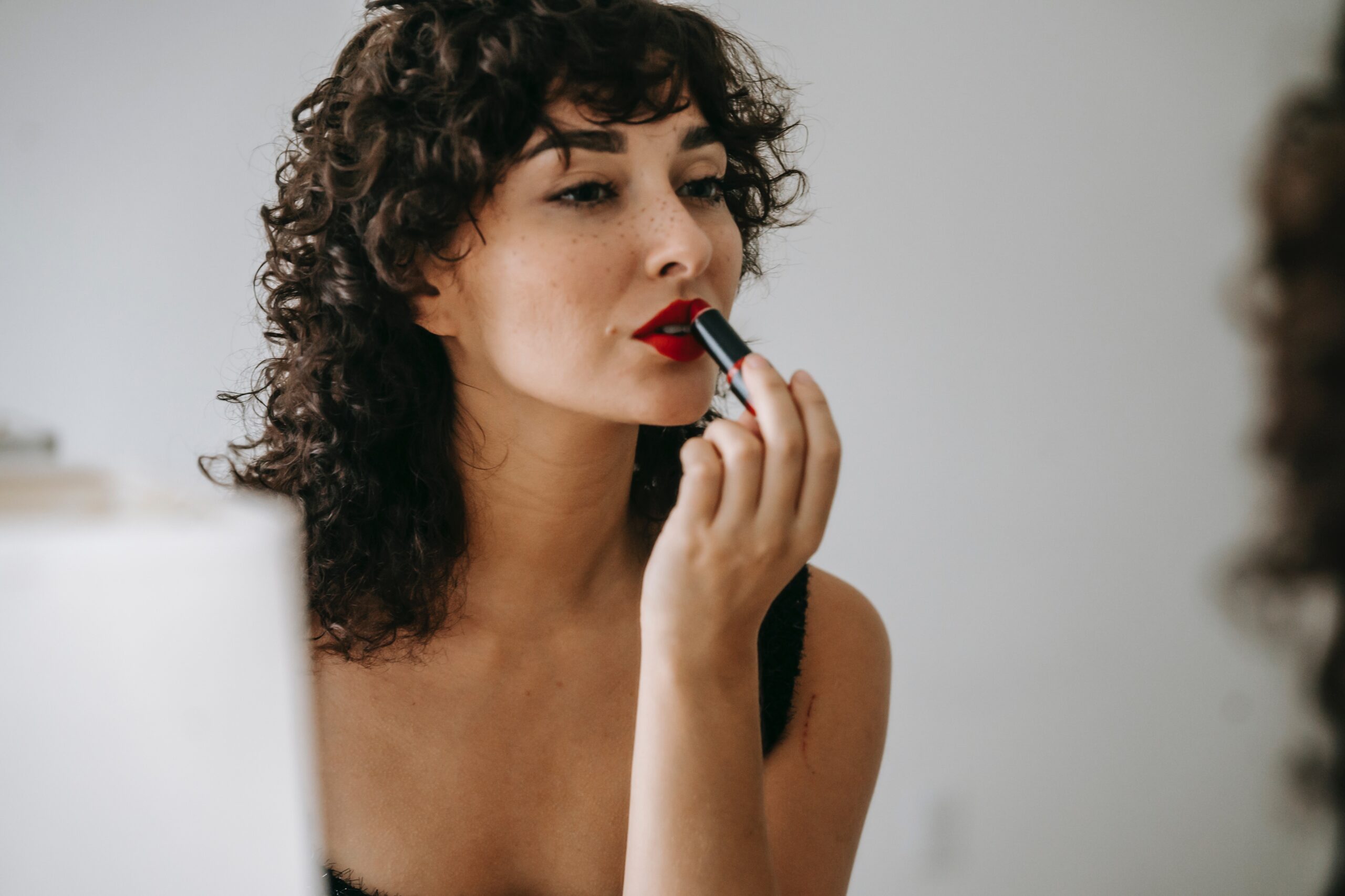 crop-gentle-woman-making-up-lips-in-front-of-mirror