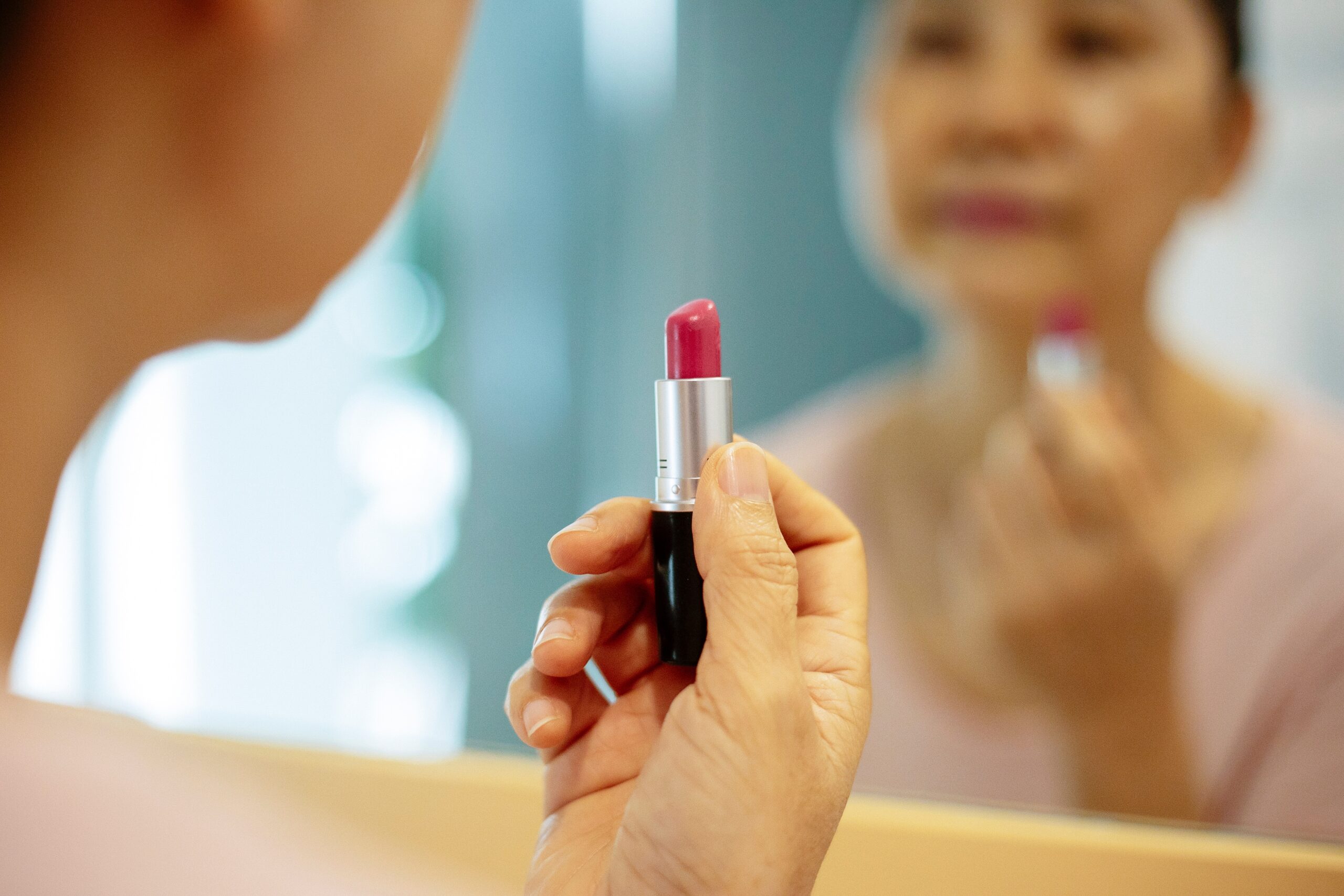 lady-applying-lipstick-while-looking-at-mirror-reflection-at-home