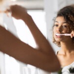 Girl Brushing Teeth With Toothbrush In Bathroom