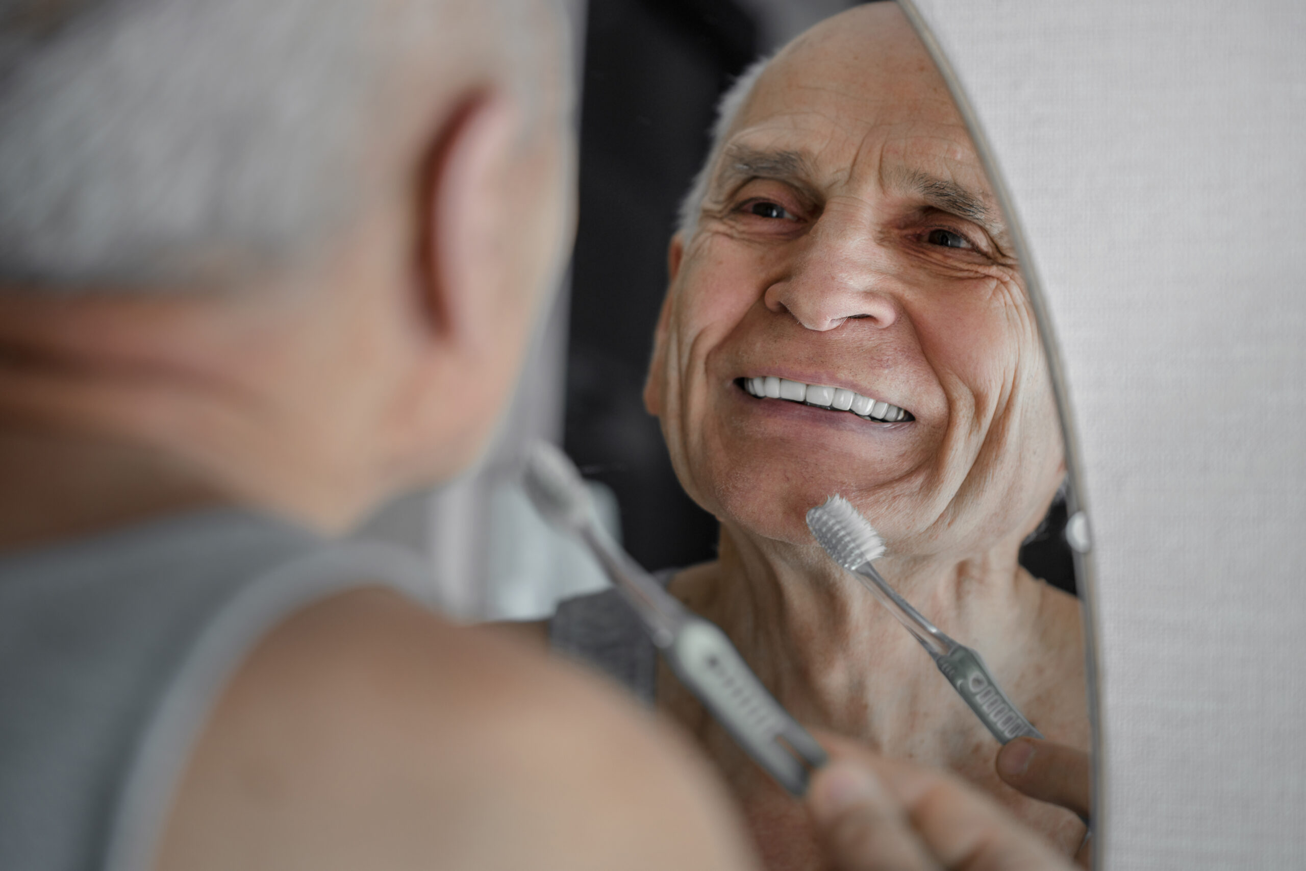 Smiling old man brushing his teeth with manual toothbrush