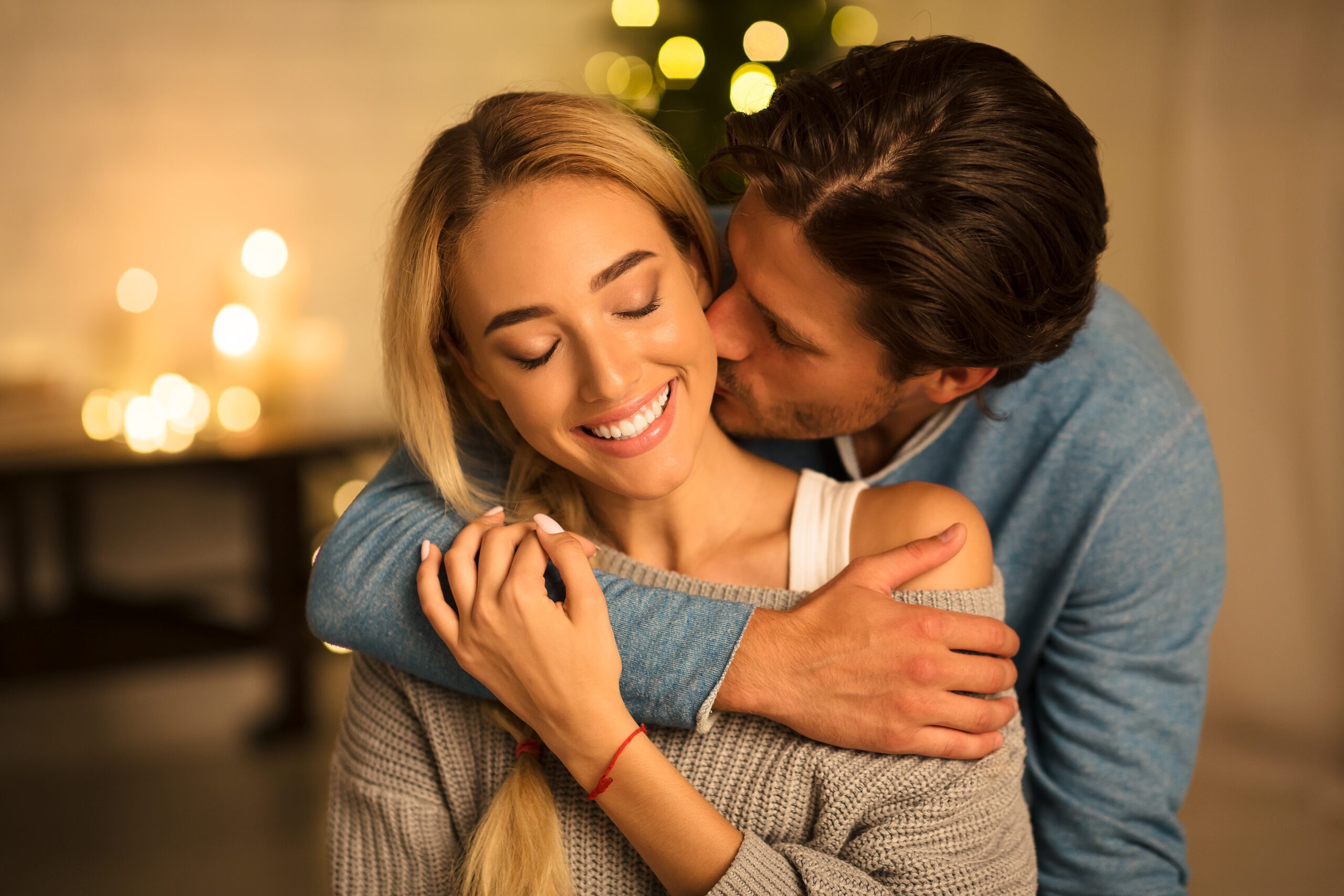 Tender moment Man-kissing wife in front of Christmas tree