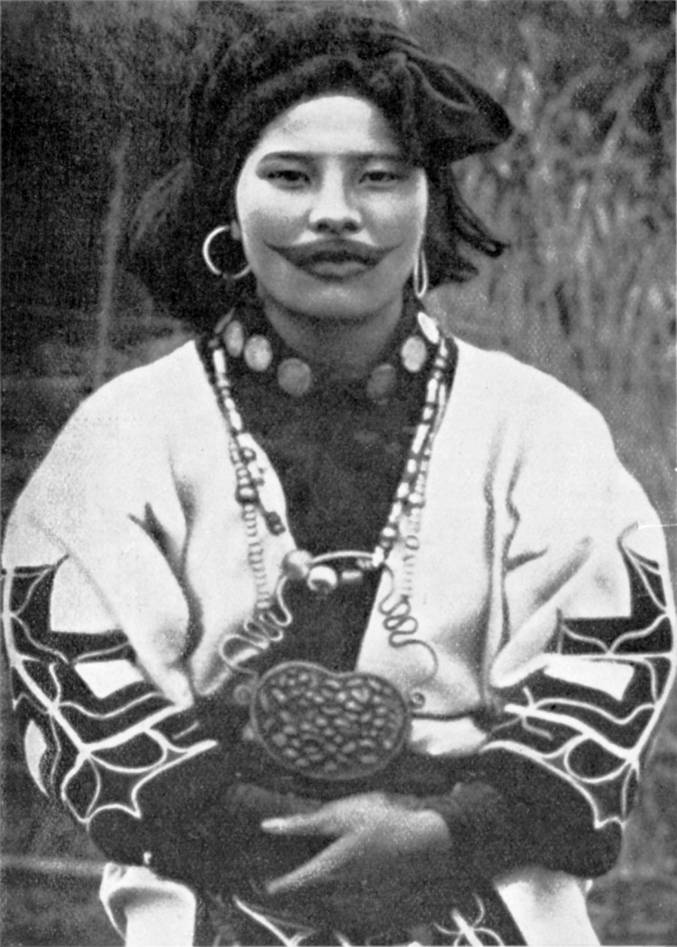 A woman with tattoos around her mouth. She wears ninkali (ear rings) in her ears, a lektumpe (necklace) around her neck, and a tamasai (necklace) down her neck